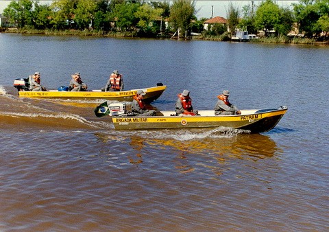 Dois barcos a motor cada um com 3 patrulheiros vestindo salva-vidas navegando pelo Rio Jacuí