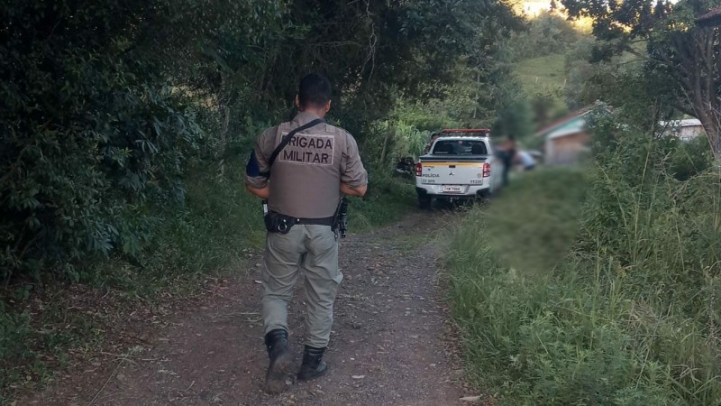 Policial Militar em uma estrada do interior e ao fundo uma viatura policial.