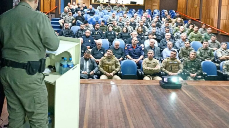 Imagem mostra um auditório lotado de agentes de segurança pública. No palco, no púlpito, um oficial da Brigada Militar fala aos presentes.