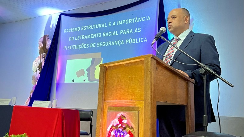 Foto mostra o delegado Fernando Sodré em frente a um púlpito, com um telão atrás